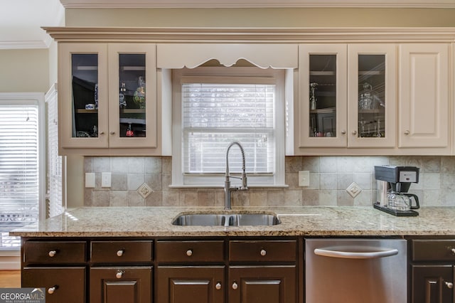 kitchen with light stone countertops, dark brown cabinetry, ornamental molding, and sink