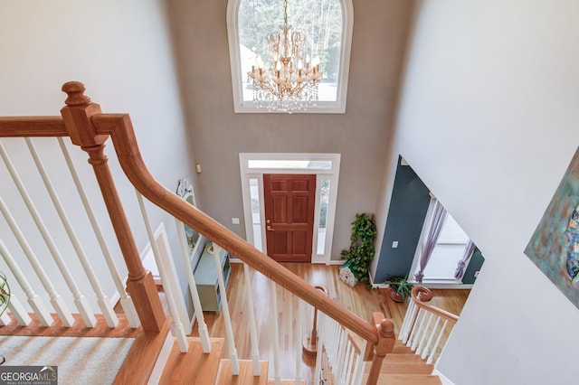 entryway with hardwood / wood-style floors, a high ceiling, and an inviting chandelier