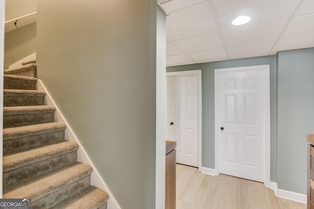 stairs with wood-type flooring and a paneled ceiling