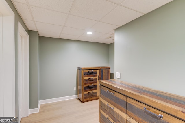 interior space with a drop ceiling, light hardwood / wood-style floors, and wood counters