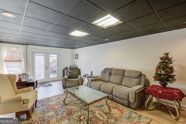 living room featuring light hardwood / wood-style flooring, a drop ceiling, and french doors