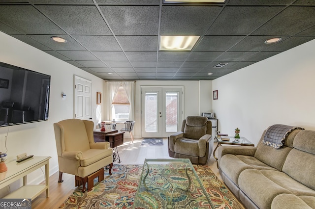 living room with a paneled ceiling, french doors, and hardwood / wood-style flooring