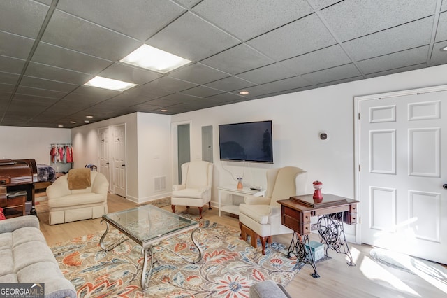 living room featuring electric panel, light hardwood / wood-style flooring, and a drop ceiling