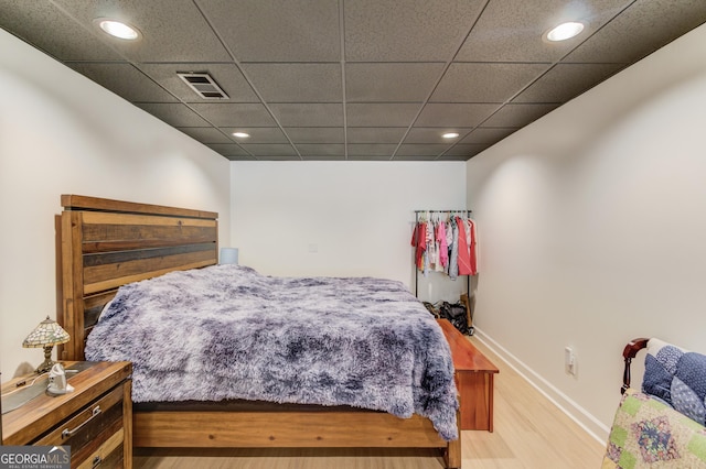 bedroom with a paneled ceiling and light hardwood / wood-style floors