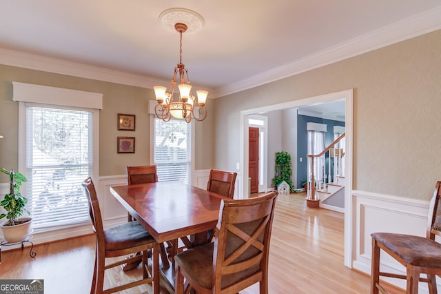 dining space featuring light hardwood / wood-style floors, ornamental molding, and an inviting chandelier