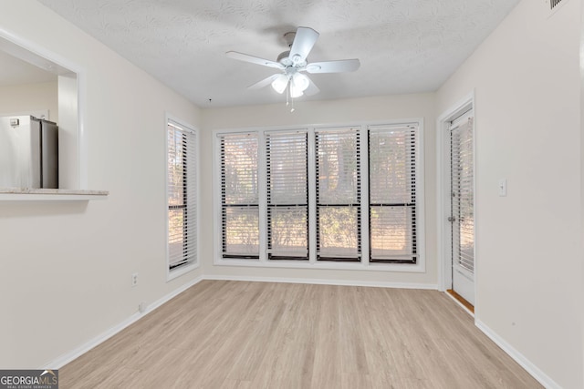 spare room with ceiling fan, a textured ceiling, and light hardwood / wood-style flooring