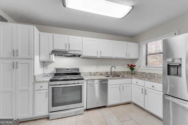 kitchen with appliances with stainless steel finishes, a textured ceiling, white cabinetry, and sink