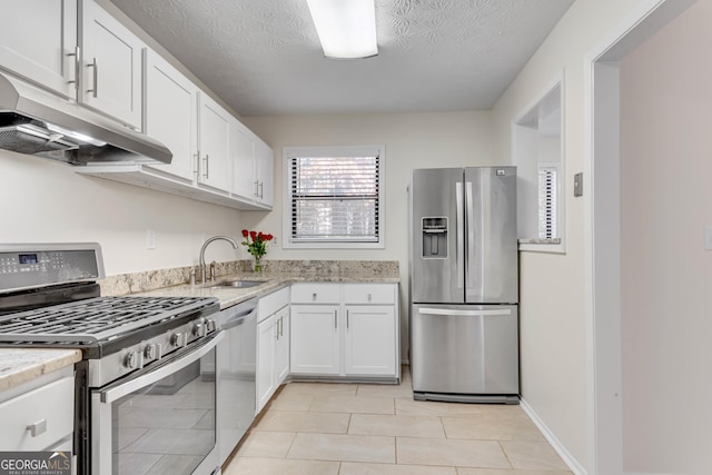 kitchen featuring sink, light tile patterned floors, a textured ceiling, white cabinetry, and stainless steel appliances