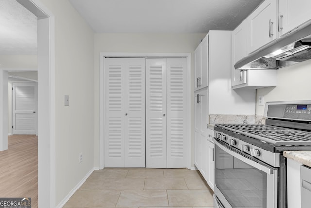 kitchen with light tile patterned flooring, white cabinetry, a textured ceiling, and stainless steel gas range