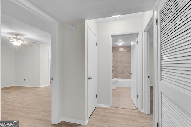 hall with light hardwood / wood-style floors and a textured ceiling