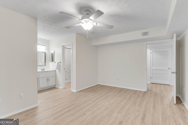 unfurnished bedroom with connected bathroom, ceiling fan, light hardwood / wood-style flooring, and a textured ceiling