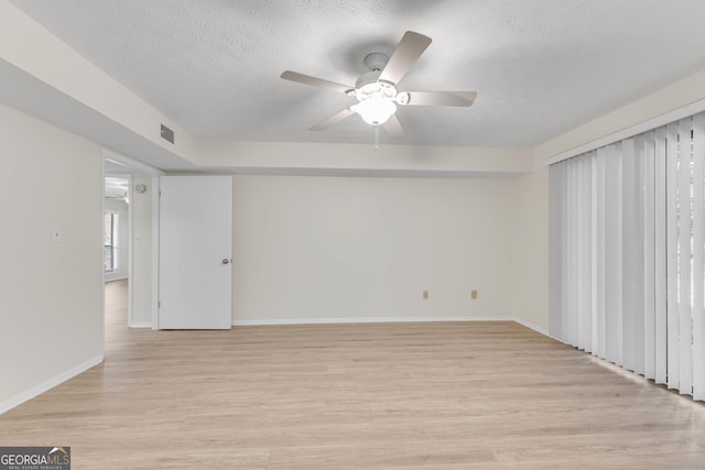 unfurnished room featuring ceiling fan, light hardwood / wood-style floors, and a textured ceiling