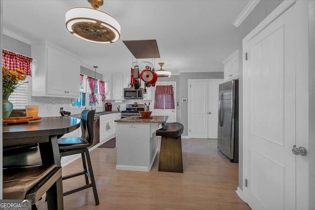 kitchen with white cabinets, a center island, crown molding, and appliances with stainless steel finishes