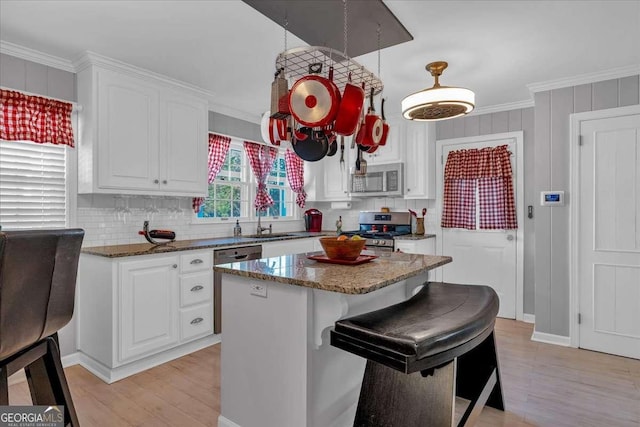 kitchen featuring a center island, white cabinets, dark stone counters, appliances with stainless steel finishes, and sink