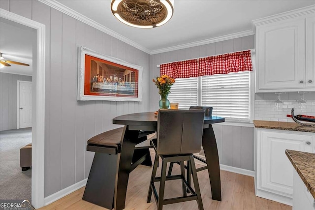 dining area with ceiling fan, crown molding, and light hardwood / wood-style flooring