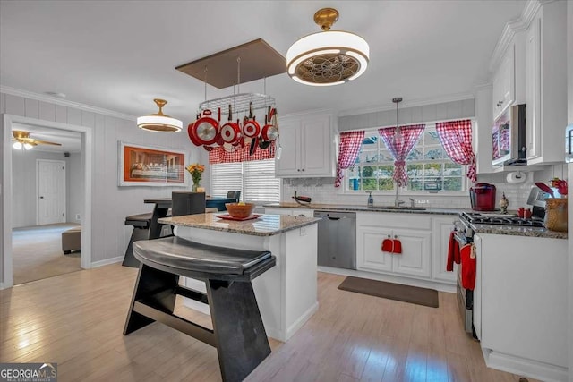 kitchen featuring stainless steel appliances, a kitchen island, white cabinetry, ceiling fan, and sink