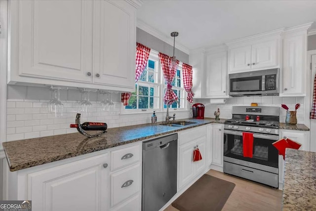 kitchen featuring stainless steel appliances, decorative light fixtures, white cabinets, and sink