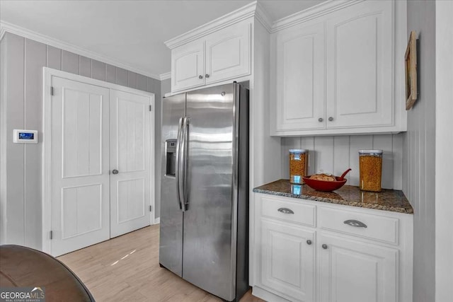 kitchen featuring white cabinetry, dark stone countertops, ornamental molding, light hardwood / wood-style flooring, and stainless steel refrigerator with ice dispenser