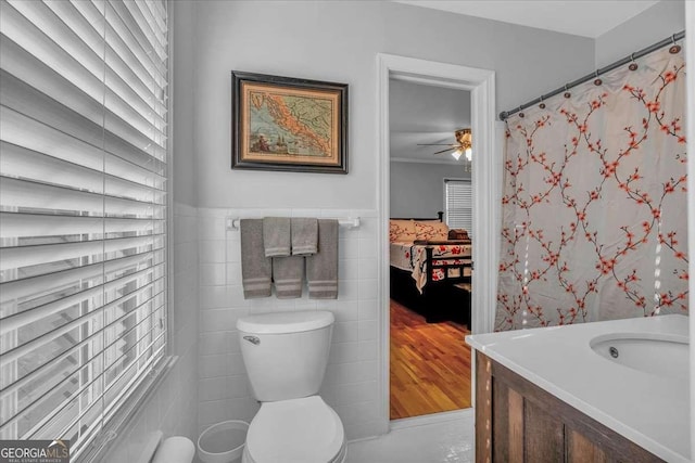 bathroom with ceiling fan, tile walls, vanity, and toilet