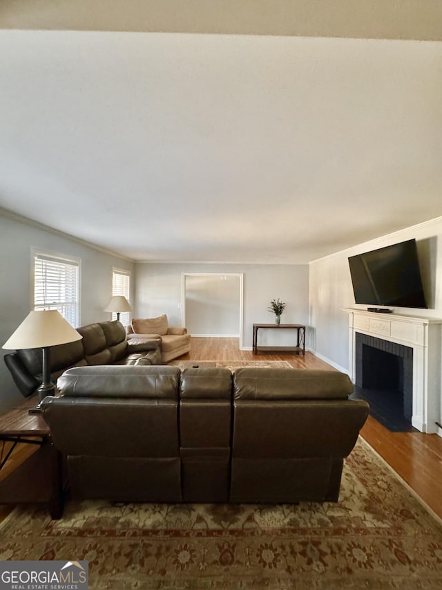 living room featuring a fireplace, crown molding, and dark hardwood / wood-style flooring