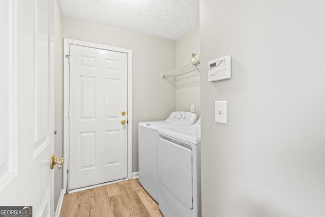 clothes washing area with separate washer and dryer, light hardwood / wood-style flooring, and a textured ceiling