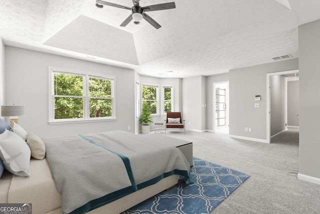 carpeted bedroom featuring a textured ceiling, a raised ceiling, and ceiling fan