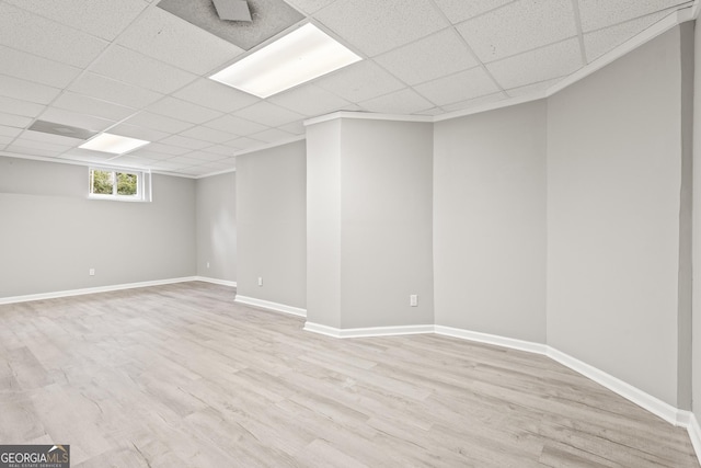 basement featuring a paneled ceiling and light hardwood / wood-style floors