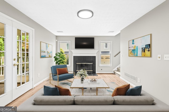 living room with a tile fireplace and light hardwood / wood-style flooring