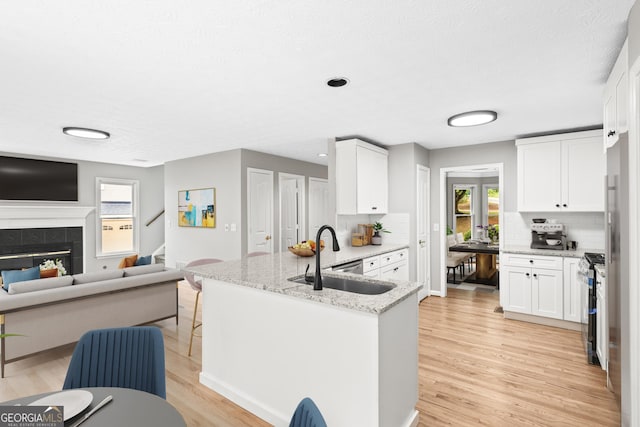 kitchen featuring white cabinets, light stone counters, light hardwood / wood-style flooring, and sink