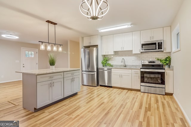 kitchen featuring hanging light fixtures, white cabinets, stainless steel appliances, and light hardwood / wood-style floors