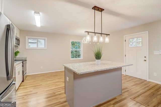 kitchen with pendant lighting, plenty of natural light, light hardwood / wood-style floors, and a kitchen island