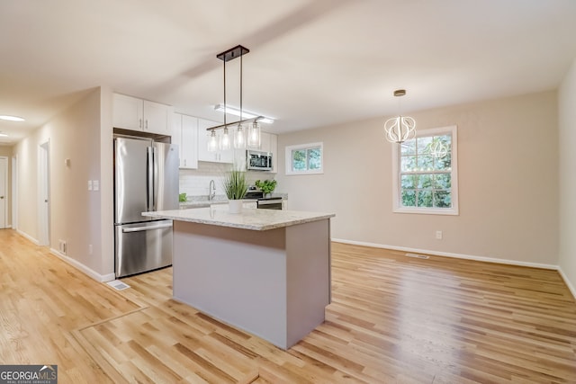 kitchen featuring light stone countertops, appliances with stainless steel finishes, light hardwood / wood-style flooring, and white cabinetry