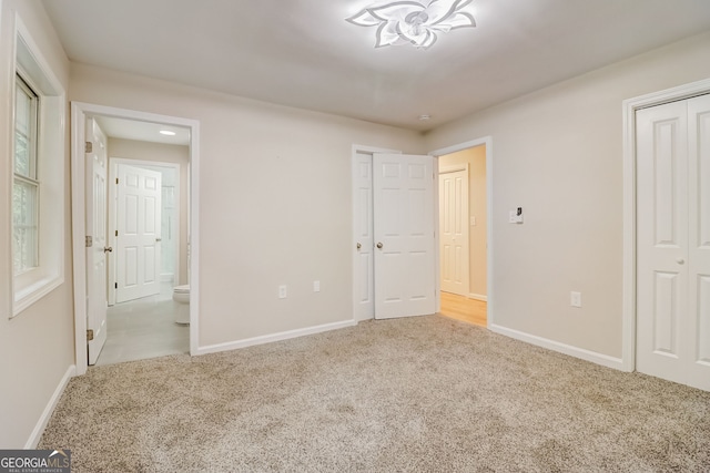 unfurnished bedroom featuring ensuite bathroom and light colored carpet