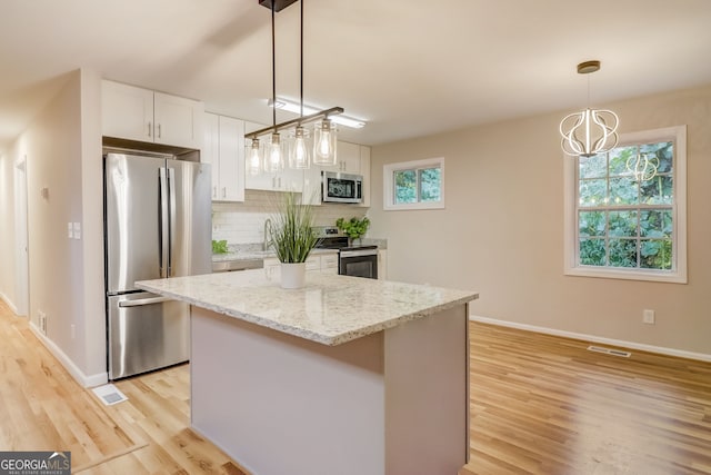 kitchen featuring white cabinets, plenty of natural light, a center island, and appliances with stainless steel finishes