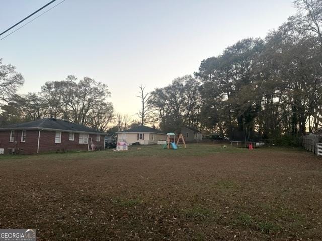 yard at dusk featuring a trampoline