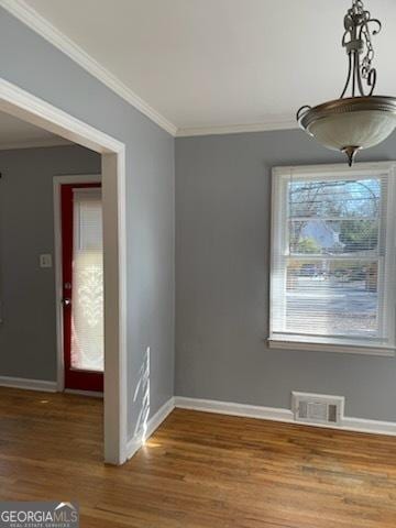 unfurnished dining area with wood-type flooring, a healthy amount of sunlight, and ornamental molding