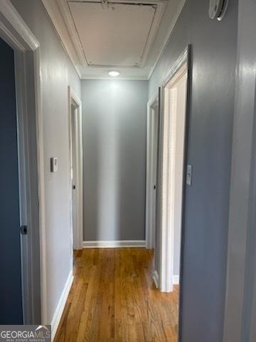 hall with light wood-type flooring and ornamental molding