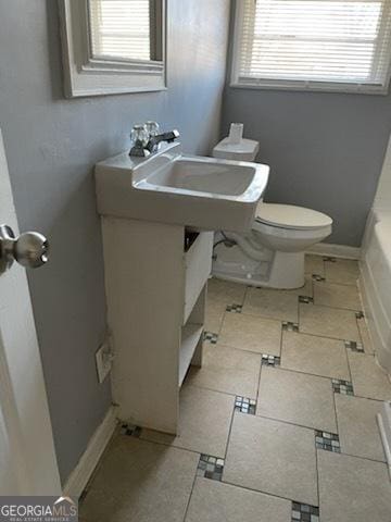 bathroom with toilet, a tub to relax in, and a wealth of natural light