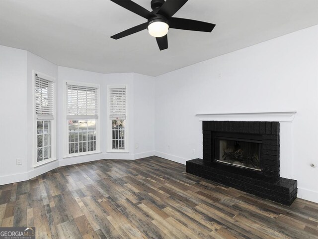 unfurnished living room featuring ceiling fan, dark hardwood / wood-style flooring, and a brick fireplace