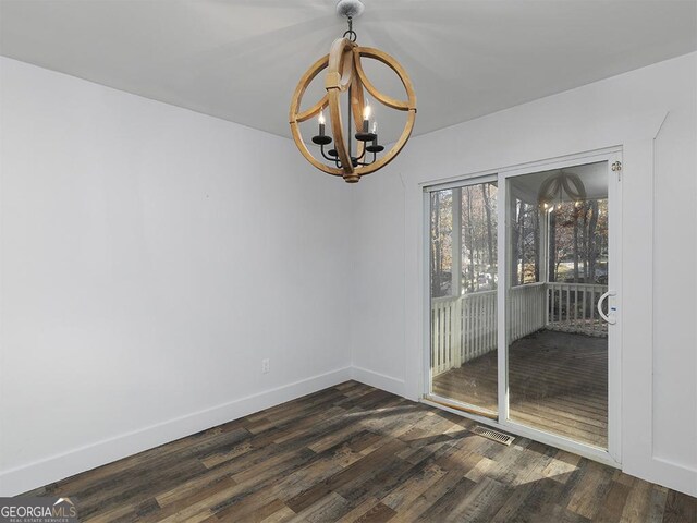 spare room featuring dark hardwood / wood-style floors and an inviting chandelier