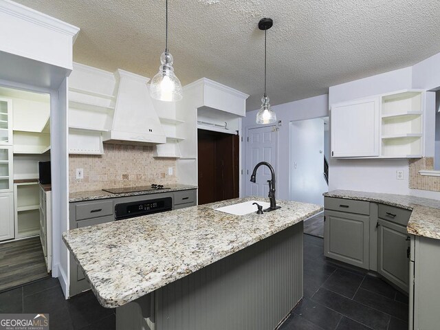 kitchen with a kitchen island with sink, sink, black appliances, and custom exhaust hood