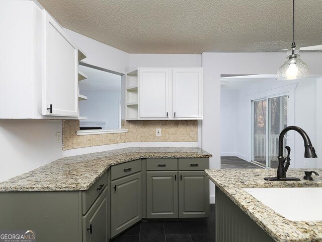 kitchen featuring decorative backsplash, white cabinetry, sink, and hanging light fixtures