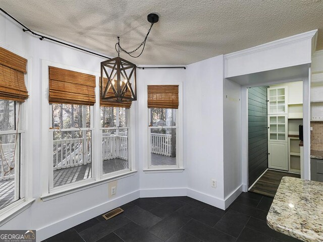 unfurnished dining area with a chandelier and a textured ceiling