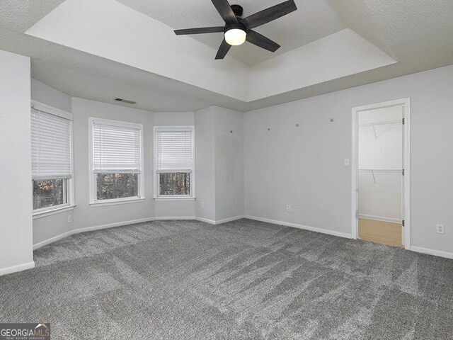 spare room featuring carpet, a textured ceiling, a raised ceiling, and ceiling fan