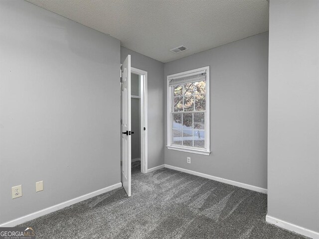 carpeted spare room with a textured ceiling