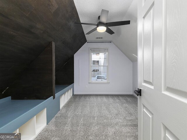 additional living space featuring carpet, a textured ceiling, vaulted ceiling, and ceiling fan