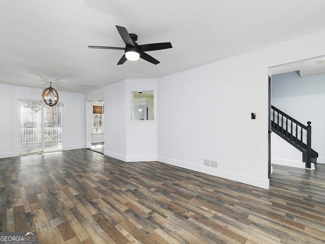 unfurnished living room featuring dark hardwood / wood-style flooring and ceiling fan with notable chandelier