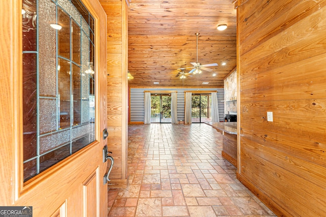 hall featuring wooden walls, wood ceiling, and lofted ceiling