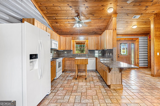 kitchen featuring a kitchen bar, tasteful backsplash, white appliances, a kitchen island, and wood walls