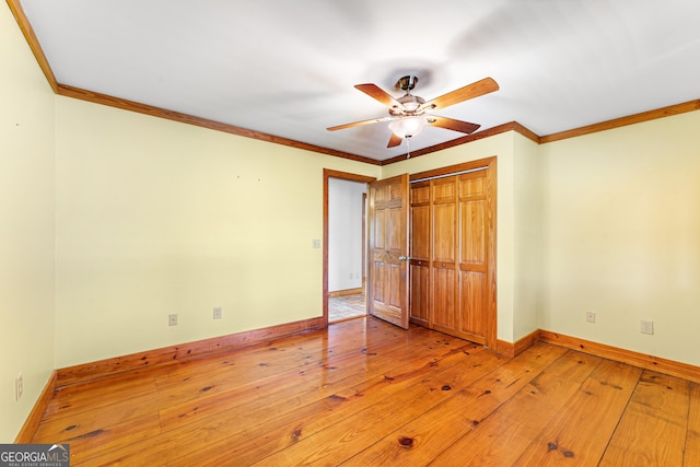 unfurnished bedroom with a closet, ceiling fan, hardwood / wood-style floors, and crown molding